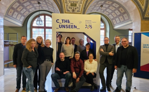 Gruppenfoto der Mitglieder des IKM vor dem Motto der Kulturhauptstadt Europas 2025 "C the Unseen".